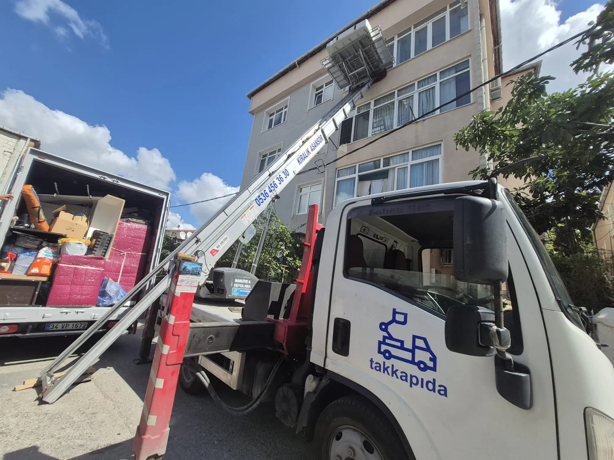 Taşıma aracının yanındaki dış cephe asansörüne yüklenen paketli eşyalar